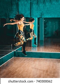 Young Attractive Brunette Woman Doing Zumba Dance And Jump Workout Alone In Gym. Toned Image.