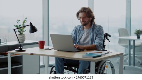 Young attractive business manager worker in wheelkchair doing work in corporate workspace. Office employee. Person with disabilities.