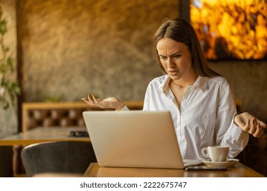 Young attractive business woman using laptop in caffe, looking worried - Shutterstock ID 2222675747