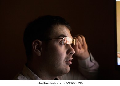Young attractive businessman alone at night sitting  computer laptop watching porn or online gambling which reflecting in his glasses isolated on black background  internet chat addiction concept