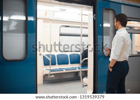 Young attractive businessman or manager entering train in metro or subway.