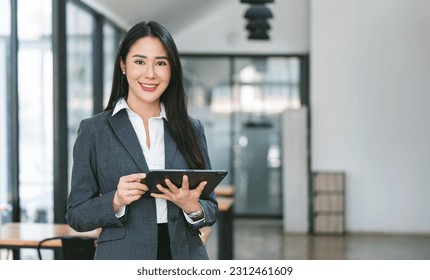 Young attractive businesswoman holding tablet, smiling to camera, standing in office.  - Powered by Shutterstock
