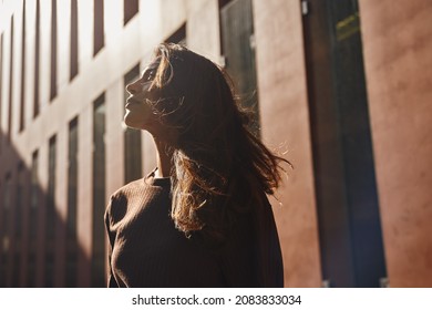Young attractive businesswoman standing against building looking at sun - Shutterstock ID 2083833034