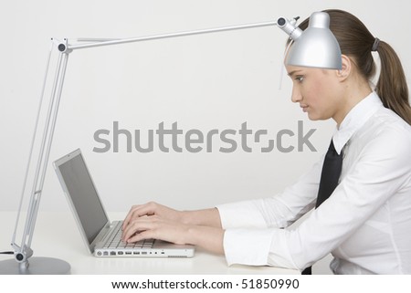 Young attractive businesswoman working on laptop computer at desk, sideview isolated on white background.