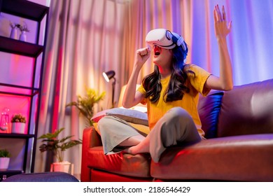 young attractive casual asian female woman watched the performance lives streaming concert in virtual reality through VR glasses goggle on sofa with fun and joyful moment in living room at home - Powered by Shutterstock