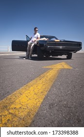 Young Attractive Caucasian Man Leaning On Muscle Car Outdoors With Reflection On Orange Striped Bonnet 