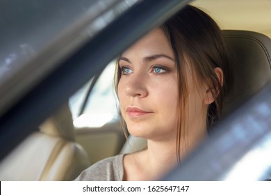 Young Attractive Caucasian Woman Behind The Wheel Driving A Car With Serious Face Expression. Attentive Look, Bright Blue Eyes. Copy Space.