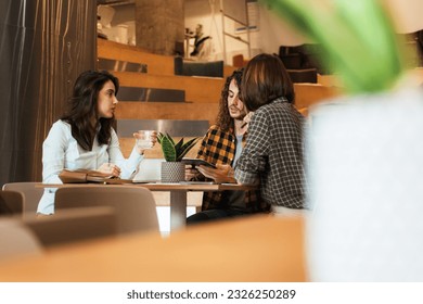Young and attractive college friends discussing about their latest exam on the tablet at the office - Shutterstock ID 2326250289