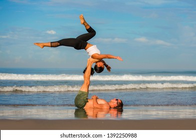 young attractive and concentrated couple of acrobats practicing acro yoga balance and meditation exercise on beautiful beach under a blue sky in mind and body control and healthy lifestyle - Shutterstock ID 1392250988