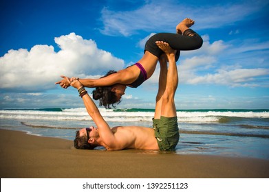 young attractive and concentrated couple of acrobats practicing acro yoga balance and meditation exercise on beautiful beach under a blue sky in mind and body control and healthy lifestyle - Shutterstock ID 1392251123