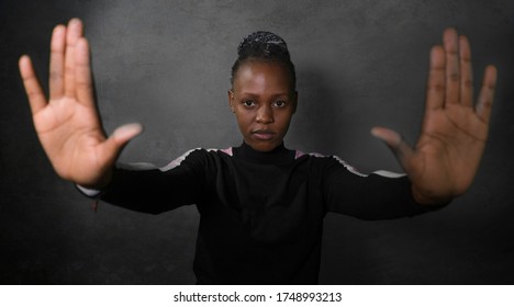 young attractive and confident afro American woman in hipster style raising up her arms and hands in stop sign demanding peace and stop racism abuse and discrimination