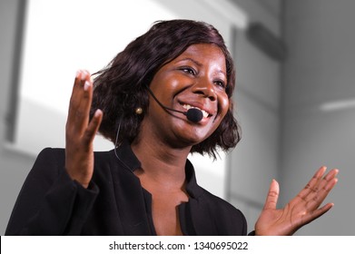 young attractive and confident black African American business woman with headset speaking in auditorium at corporate training event or seminar giving motivation and success coaching conference