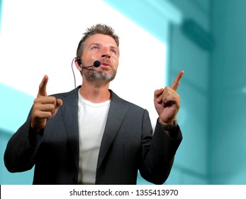 Young Attractive And Confident Successful Man With Headset Speaking At Corporate Business Coaching And Training Auditorium Conference Room Talking Giving Motivation Training From Speaker Stage