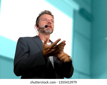 Young Attractive And Confident Successful Man With Headset Speaking At Corporate Business Coaching And Training Auditorium Conference Room Talking Giving Motivation Training From Speaker Stage