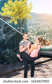 Young Attractive Couple Doing Advanced Double Dare Crunches While Standing On Rooftop Of The Building In Urban Area.