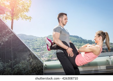 Young Attractive Couple Doing Advanced Double Dare Crunches While Standing On Rooftop Of The Building In Urban Area.