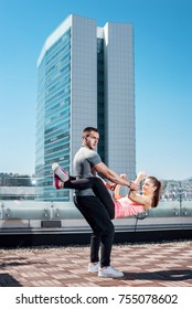 Young Attractive Couple Doing Advanced Double Dare Crunches While Standing On Rooftop Of The Building In Urban Area.