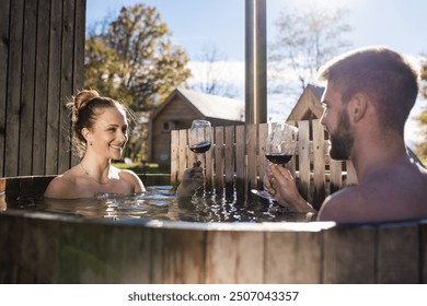 Young attractive couple enjoying a private wooden hot tub during a glamping vacation. Romantic weekend getaway concept. - Powered by Shutterstock