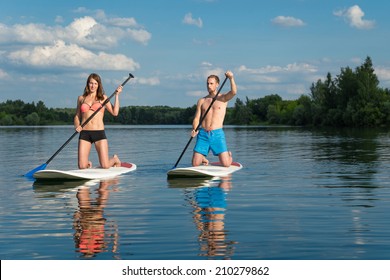 Young Attractive Couple Knees On Stand Up Paddle Board In The Lake, SUP