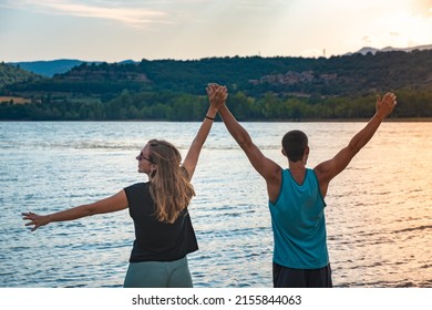 Young Attractive Couple open arms holding hands in a Beautiful Lake in summer during sunset. Discovery Travel love Destination Concept.