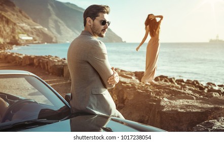 
 Young attractive couple posing in a convertible car, by the sea