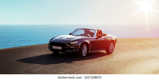 
 Young attractive couple posing in a convertible car, by the sea
