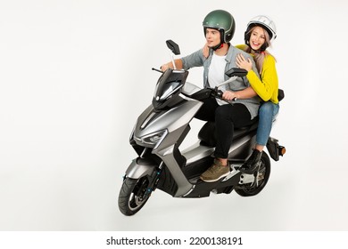 young attractive couple riding an electric motorbike scooter happy having fun together, stylish hipster man and woman isolated on white studio background wearing safety helmets speed action