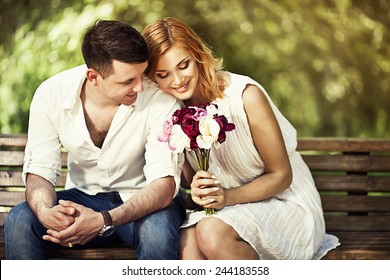 Young attractive couple sitting on bench in the park and romantic smiling.