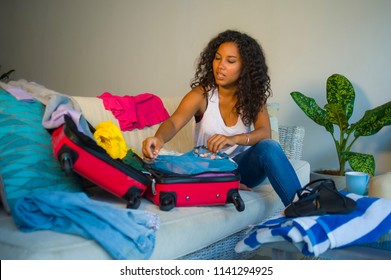 Young Attractive And Crazy Happy Black Afro American Woman Preparing Clothes Packing Stuff In Suitcase Leaving For Holidays Trip Excited And Messy In Travel Vacations And Tourism Concept