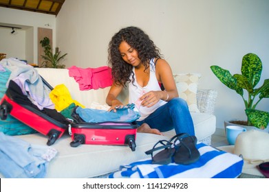 Young Attractive And Crazy Happy Black Afro American Woman Preparing Clothes Packing Stuff In Suitcase Leaving For Holidays Trip Excited And Messy In Travel Vacations And Tourism Concept