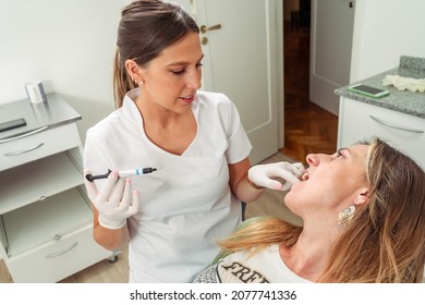 Young And Attractive Dentist Performing Adhesive Cement Treatment On A Beautiful Patient. Concept Dental Care, Health Care.