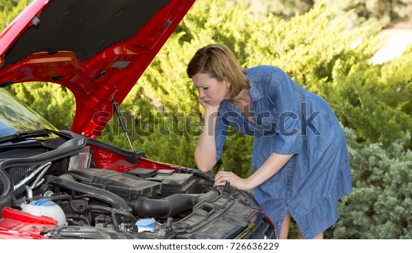 young
attractive desperate and confused woman stranded on roadside
looking worried to broken car engine failure or crash accident in
automobile road assistance and insurance
concept