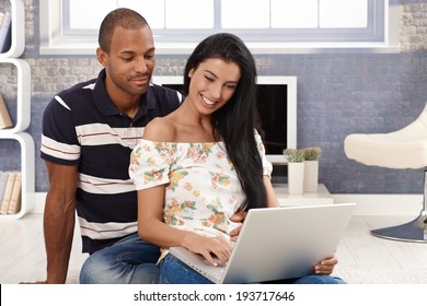 Young Attractive Diverse Couple Browsing Internet, Using Laptop Computer, Smiling.