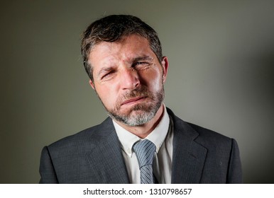 young attractive exhausted and stressed businessman in suit and tie feeling tired and bored in overwhelmed and frustrated face expression isolated on background in corporate company lifestyle