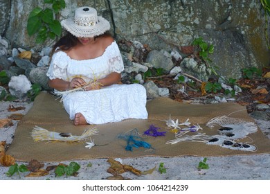 Young attractive and exotic Polynesian Cook Islander woman weaving a hand fan in Rarotonga, Cook Islands. Real people. Copy space