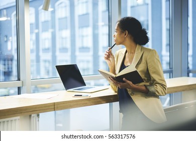 Young attractive female afro american chief economist in company planning formal meeting with partners using laptop computer with blank screen connected to wifi standing on copy space for advertising