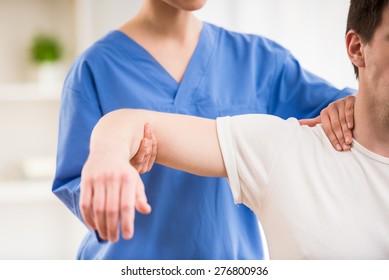 Young attractive female doctor making neck massage to male patient.