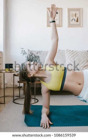 Young attractive female doing yoga in her living room.
