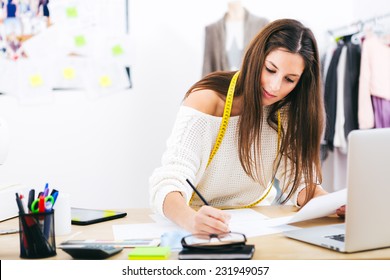 Young Attractive Female Fashion Designer Leaning On Office Desk, Working With A Laptop At Home