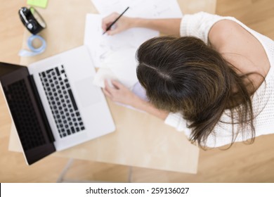 Young attractive female fashion designer top view leaning on office desk, working with a laptop at home