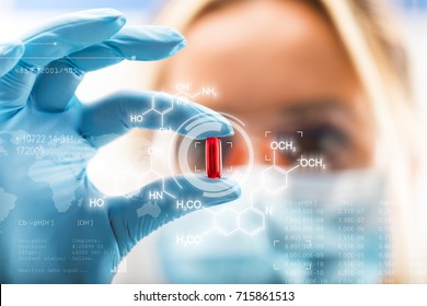 Junge attraktive Wissenschaftlerin, die eine rote, transparente Pille mit futuristischer wissenschaftlicher Luft-Schnittstelle mit chemischen Formeln und Forschungsdaten im Vordergrund hält