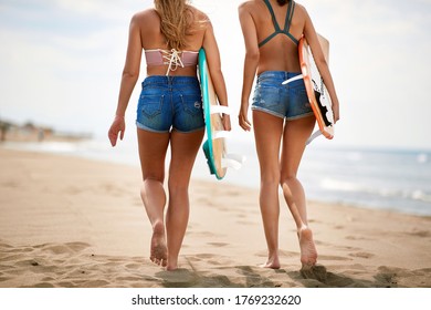 Young attractive female surfers stroll a beach on a beautiful weather