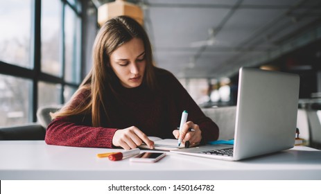 Young attractive female writer scribing notes to textbook prepare for exam, girl doing homework sitting desktop with modern laptop computer, woman making plan for tomorrow and creating  to do list - Shutterstock ID 1450164782