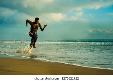 Young Attractive Fit Athletic And Strong Black African American Man Running At The Beach Training Hard And Sprinting On Sea Water In Professional Athlete Lifestyle And Ripped Runner Workout 