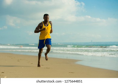 Young Attractive Fit Athletic And Strong Black African American Man Running At The Beach Training Hard And Sprinting On Sea Water In Professional Athlete Lifestyle And Ripped Runner Workout 