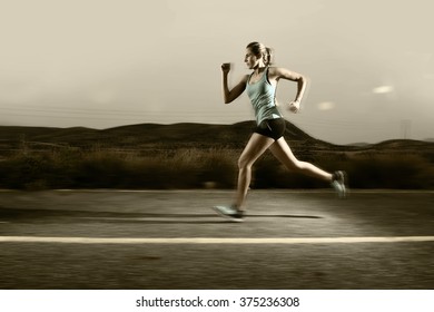 young attractive and fit sport woman running outdoors on asphalt road in mountain landscape on evening with harsh light in fitness workout training shot in motion blurred advertising style - Powered by Shutterstock