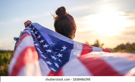 Young attractive girl holding a waving US flag. Patriot country. American voters.