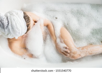 A young attractive girl relaxes in the bathroom and rests against the backdrop of a beautiful light interior. Spa treatments for beauty and health with skin care