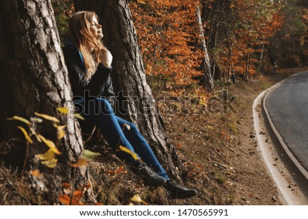 Young attractive girl sitting between trees in forest