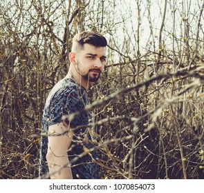 young attractive guy with beard posing on nature in thickets
